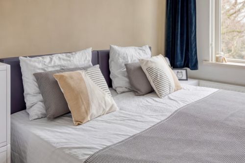 Stylish CUBIQZ slipcover for double bed headboard, transforming a cardboard bed into a realistic bedroom presentation.
